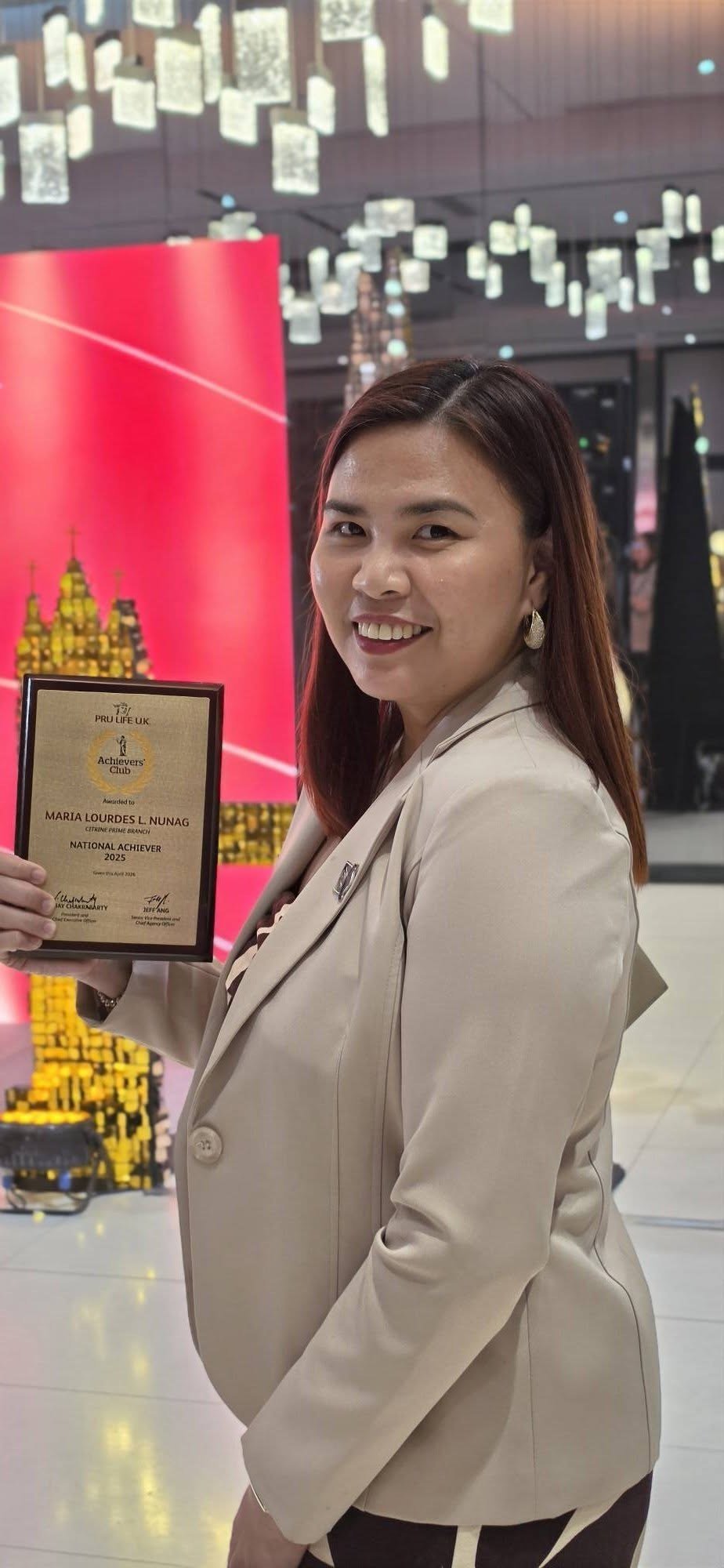 Maria Lourdes Nunag holding a professional achievement plaque